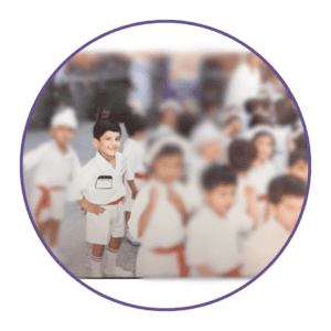 Child practicing martial arts in a group class, wearing a white uniform and red belt.