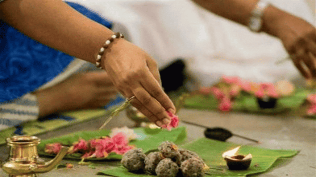 Devotees perform Pitru Puja with offerings on a sacred leaf for ancestral blessings.