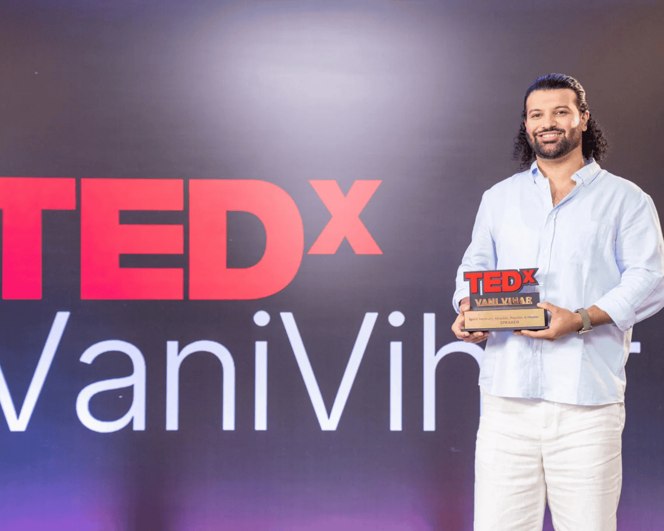 Psychic medium Daksh holding a TEDx talk award at VaniVibha event.